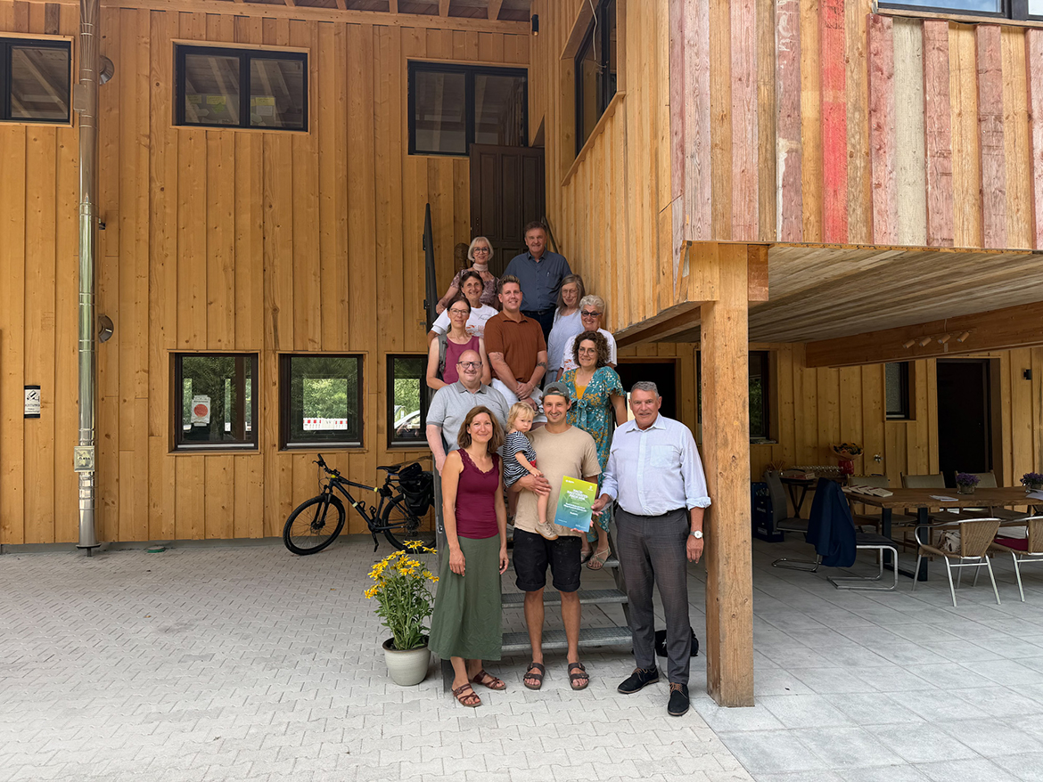 Einige Menschen stehen hintereinander auf der Treppe eines großen Holzhauses